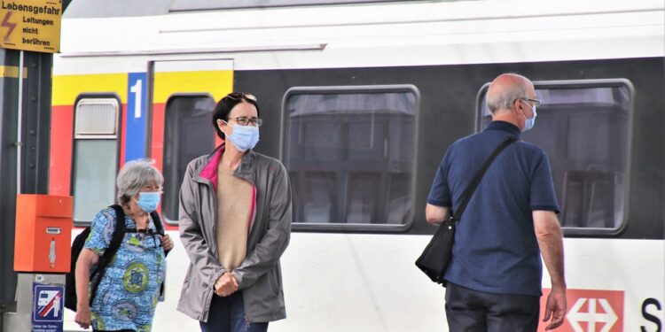 Persone con mascherina in attesa del treno