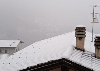 La neve sui tetti di San Bartolomeo Val Cavargna. Sullo sfondo, l'abitato di Cusino